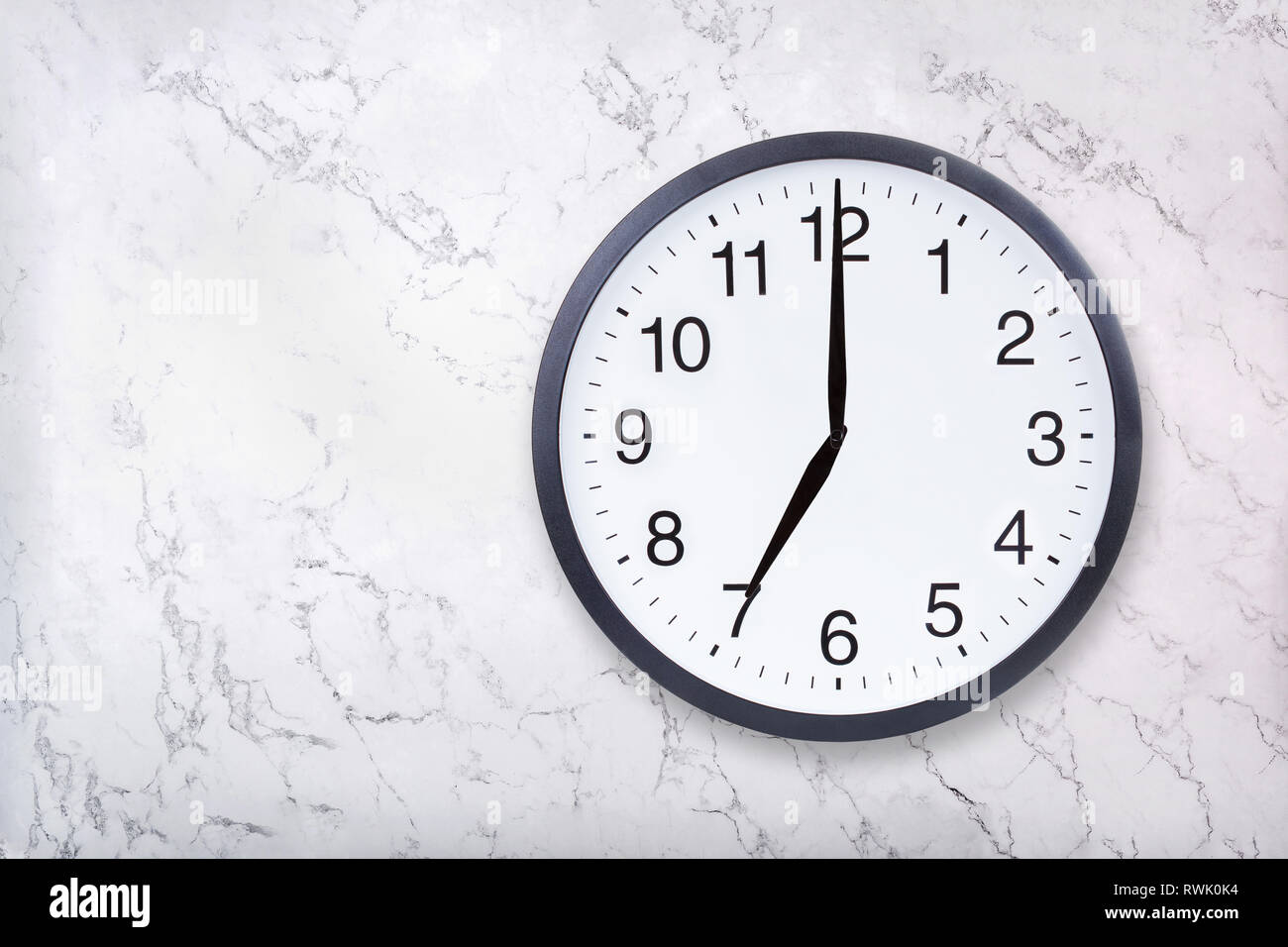 Orologio da parete visualizza ore sette su marmo bianco texture. Ufficio Mostra orologio 7pm o le 7am Foto Stock