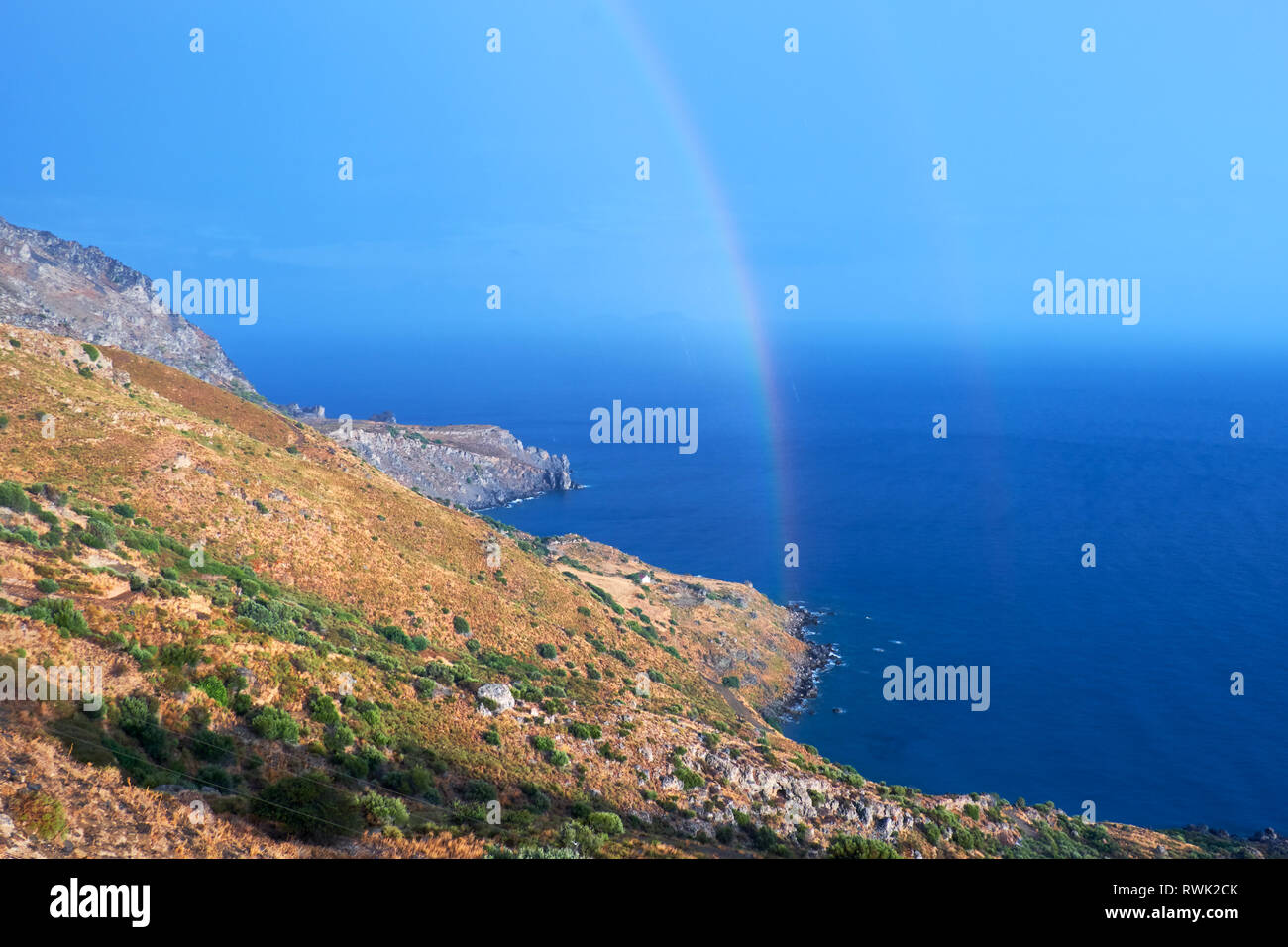Selvatica costa collinare di Creta isola dopo una pioggia con un arcobaleno Foto Stock