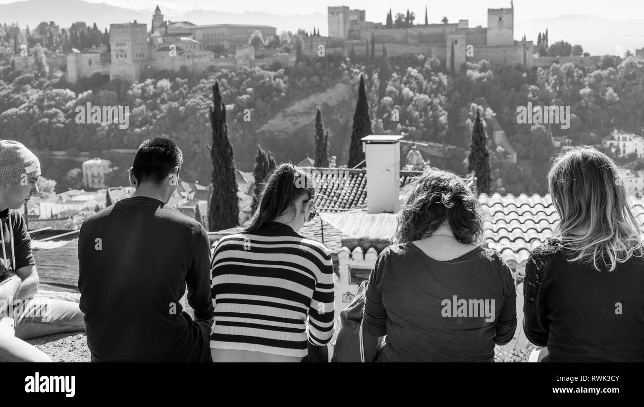 Turisti che si siedono in vista dell'Alhambra; Granada, Andalusia, Spagna Foto Stock