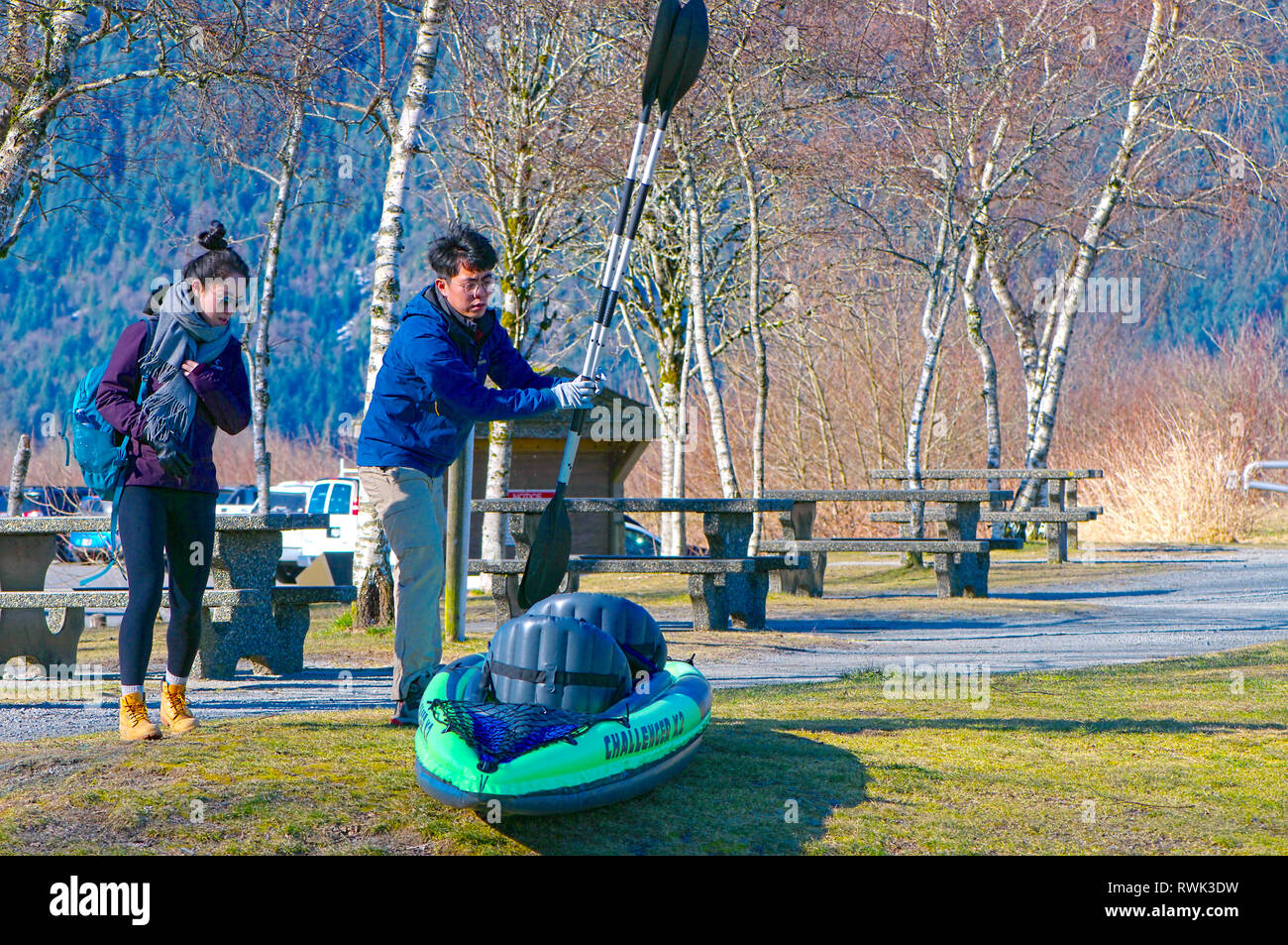 Giovani asiatici giovane con il loro kayak gonfiabili e le palette nell'area pic-nic di concessione si restringe il Parco Regionale, B.C., Canada Foto Stock