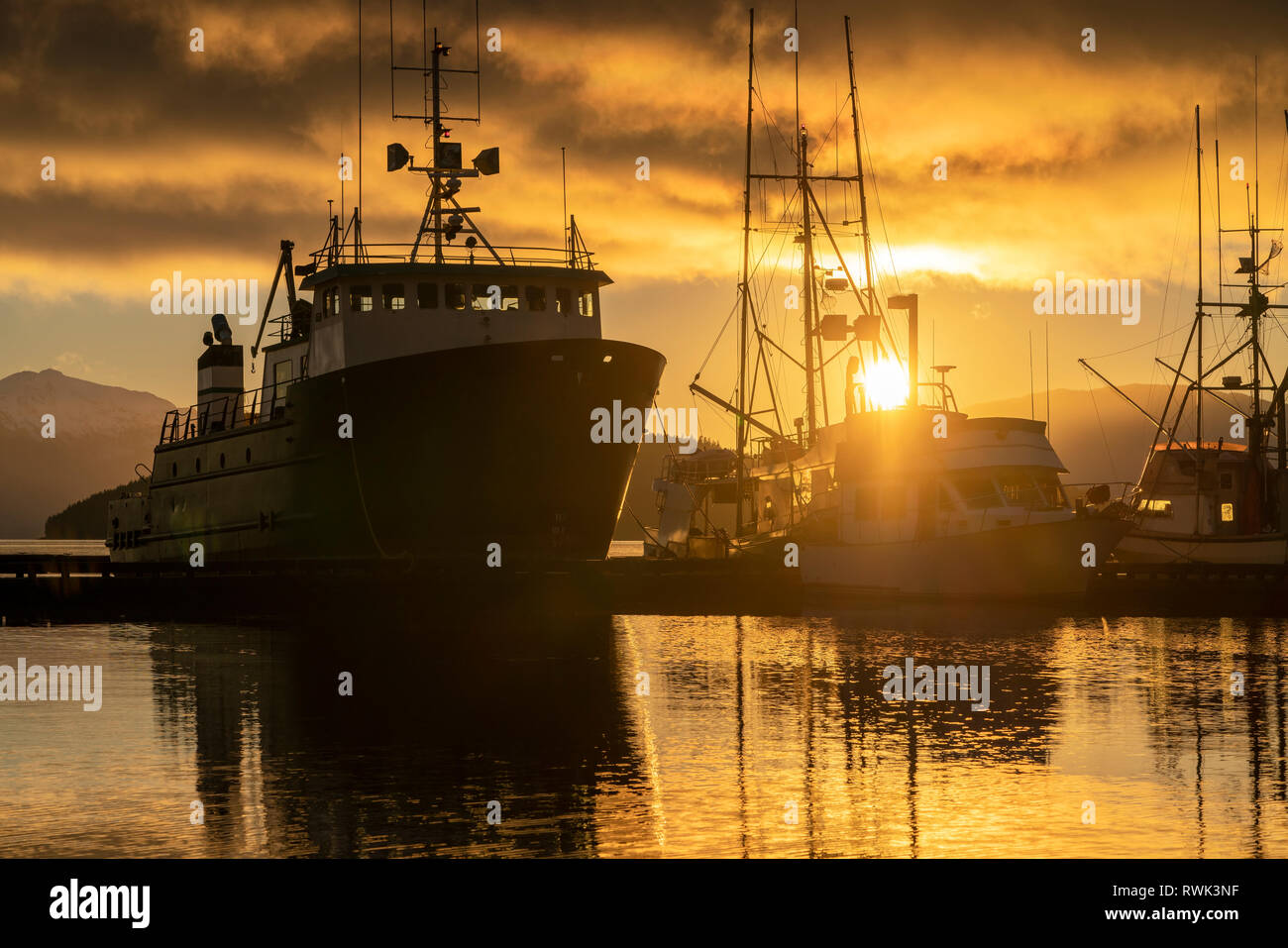 Commerciale barche da pesca in Auke Bay al tramonto, Alaska sudorientale; Juneau, Alaska, Stati Uniti d'America Foto Stock