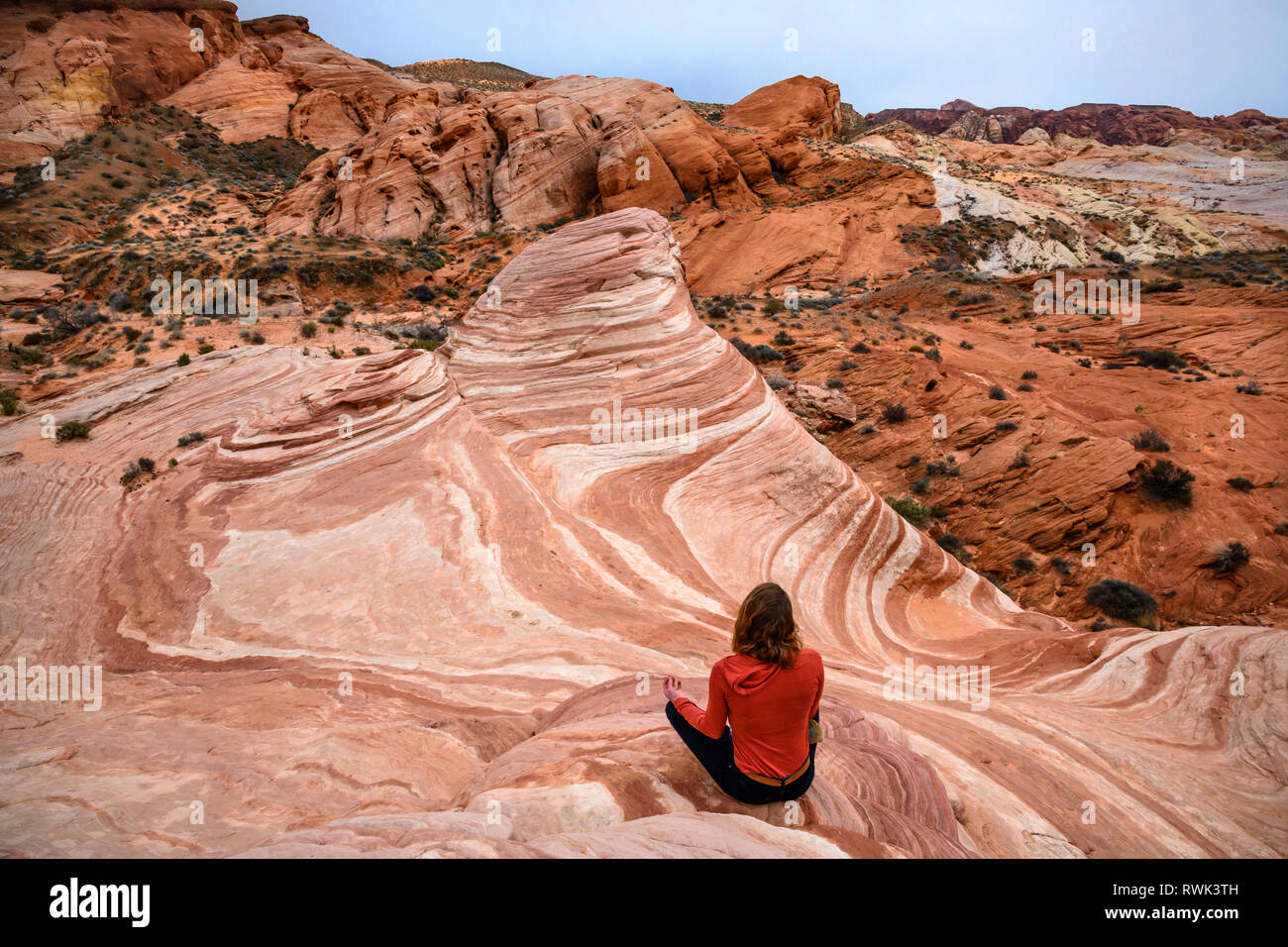 Donna seduta in meditazione porre al fuoco di arenaria wave rock formazione della Valle di Fire State Park, Nevada. Foto Stock