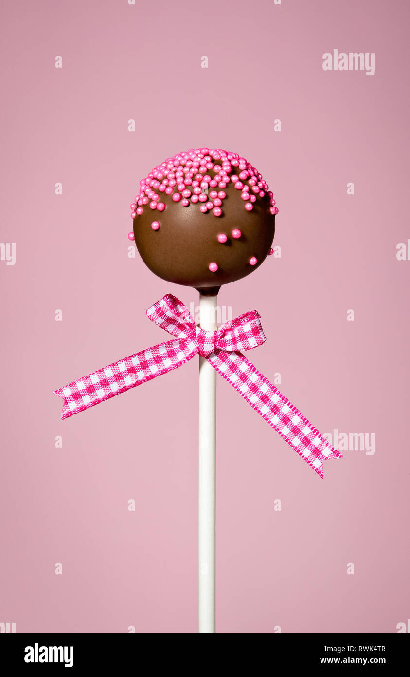 Torta al cioccolato di pop con nastro su un sfondo rosa Foto Stock