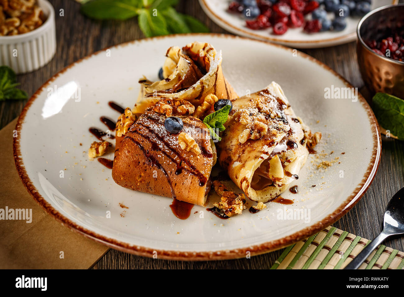 Crepes con crema di cioccolato decorate con noci e salsa al cioccolato Foto Stock