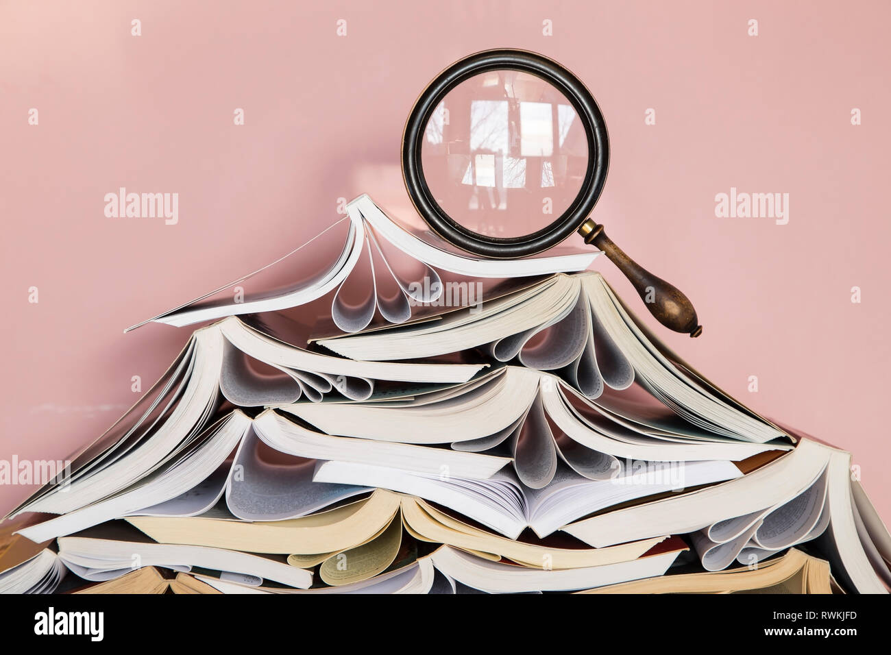 Pila di libri con una lente di ingrandimento Foto Stock