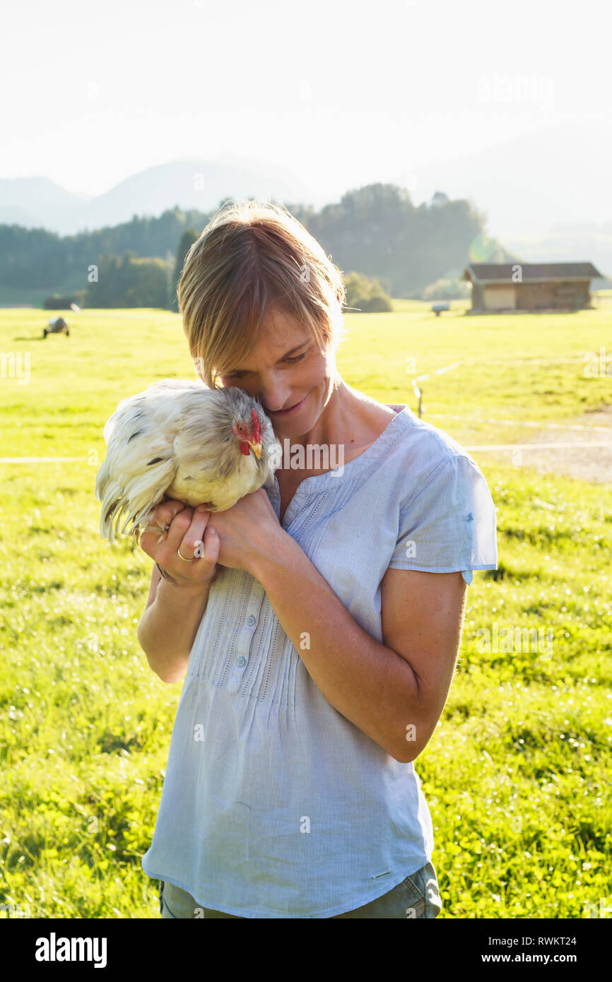 La donna che porta il gallo in campagna, a Sonthofen, Baviera, Germania Foto Stock