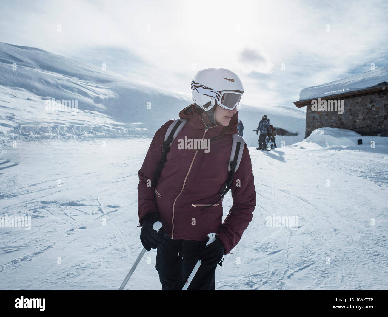 Femmina giovane sciatore indossando il casco e occhiali da sci guardando indietro nel paesaggio innevato, Alpe Ciamporino, Piemonte, Italia Foto Stock