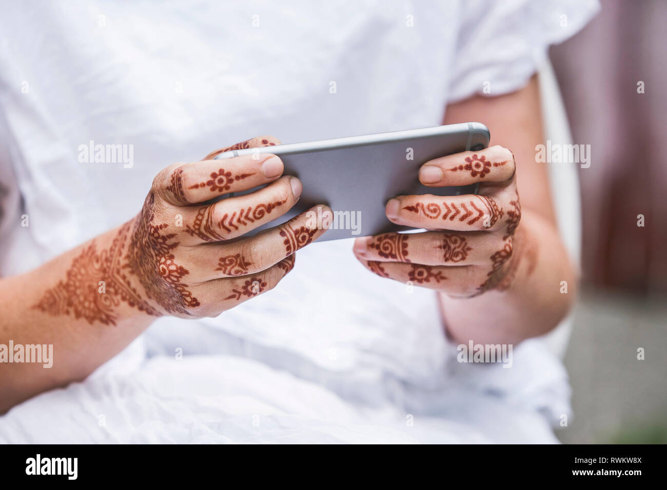 Donna con henna tattoo sulle mani utilizza lo smartphone Foto Stock