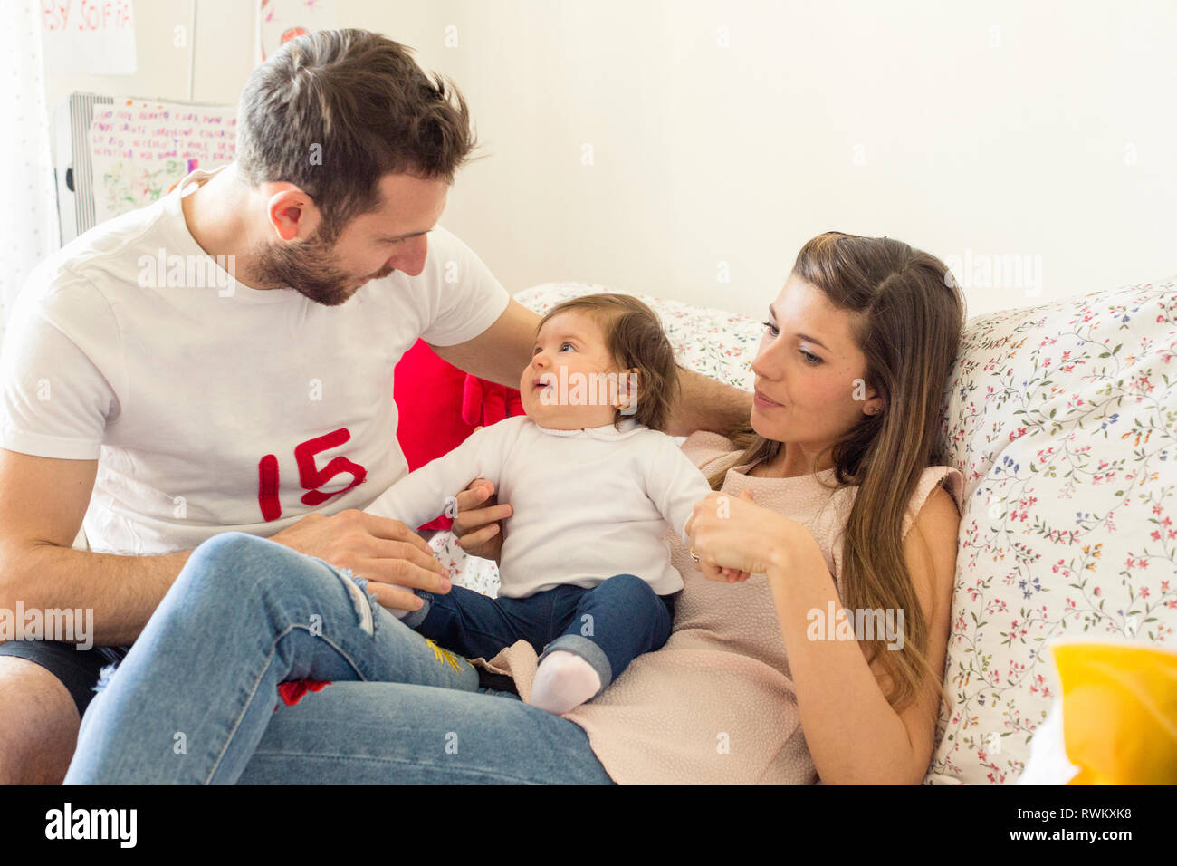 I genitori a parlare con il bambino ragazza sul divano Foto Stock