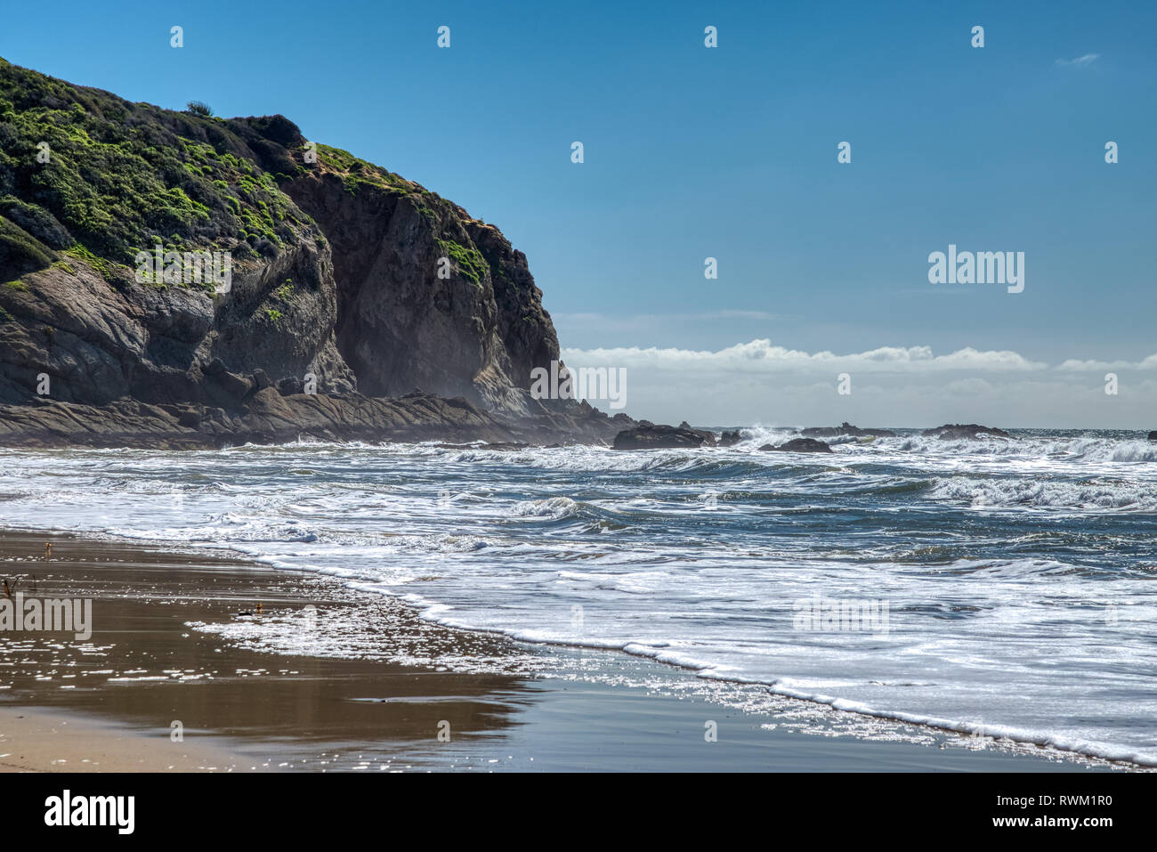 Pittoresca vista costiera di gigantesche scogliere a sorge sulla spiaggia di una giornata soleggiata con riflessi nell'acqua, Dana Point, California Foto Stock