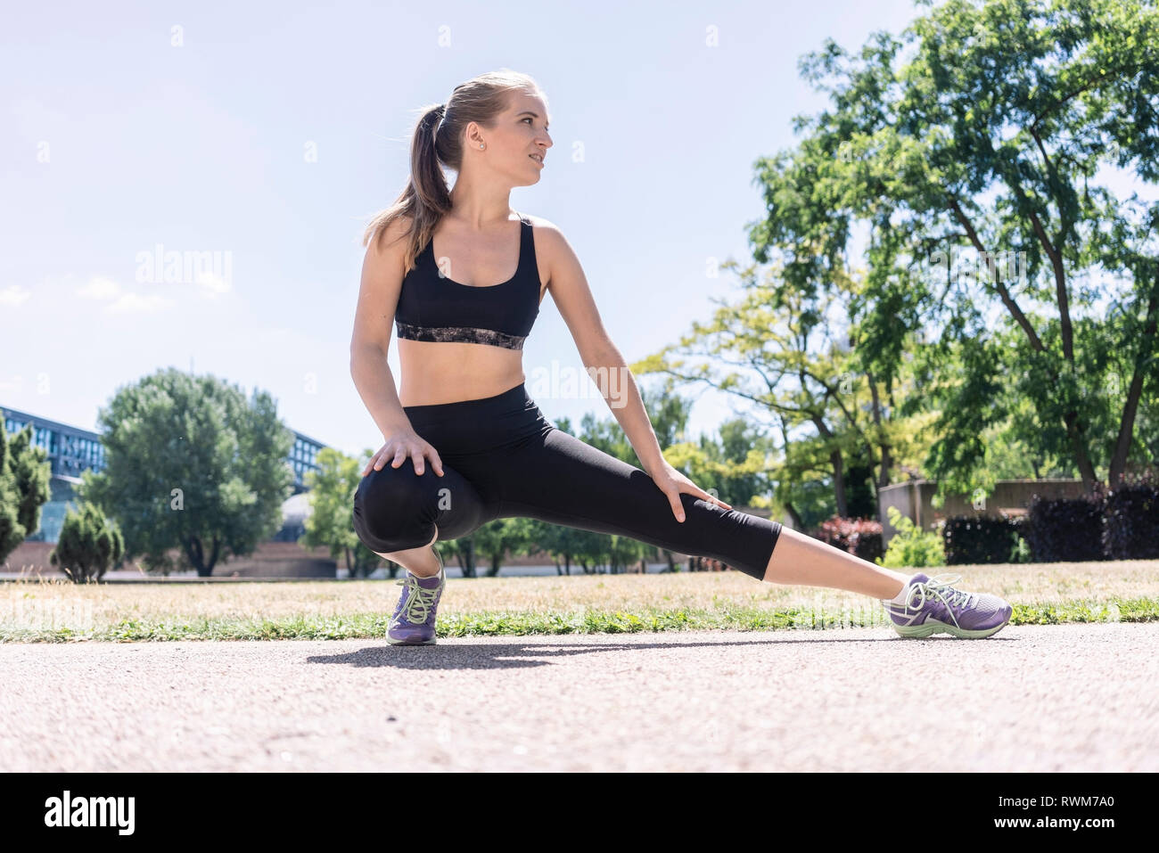 Giovane donna stretching nel parco della città di Berlino, Germania Foto Stock