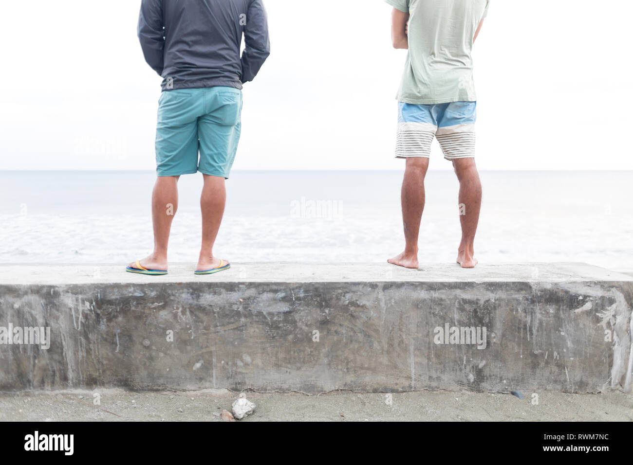 Gli uomini sulla parete affacciata sul mare e la pressa, Aurora, Filippine Foto Stock