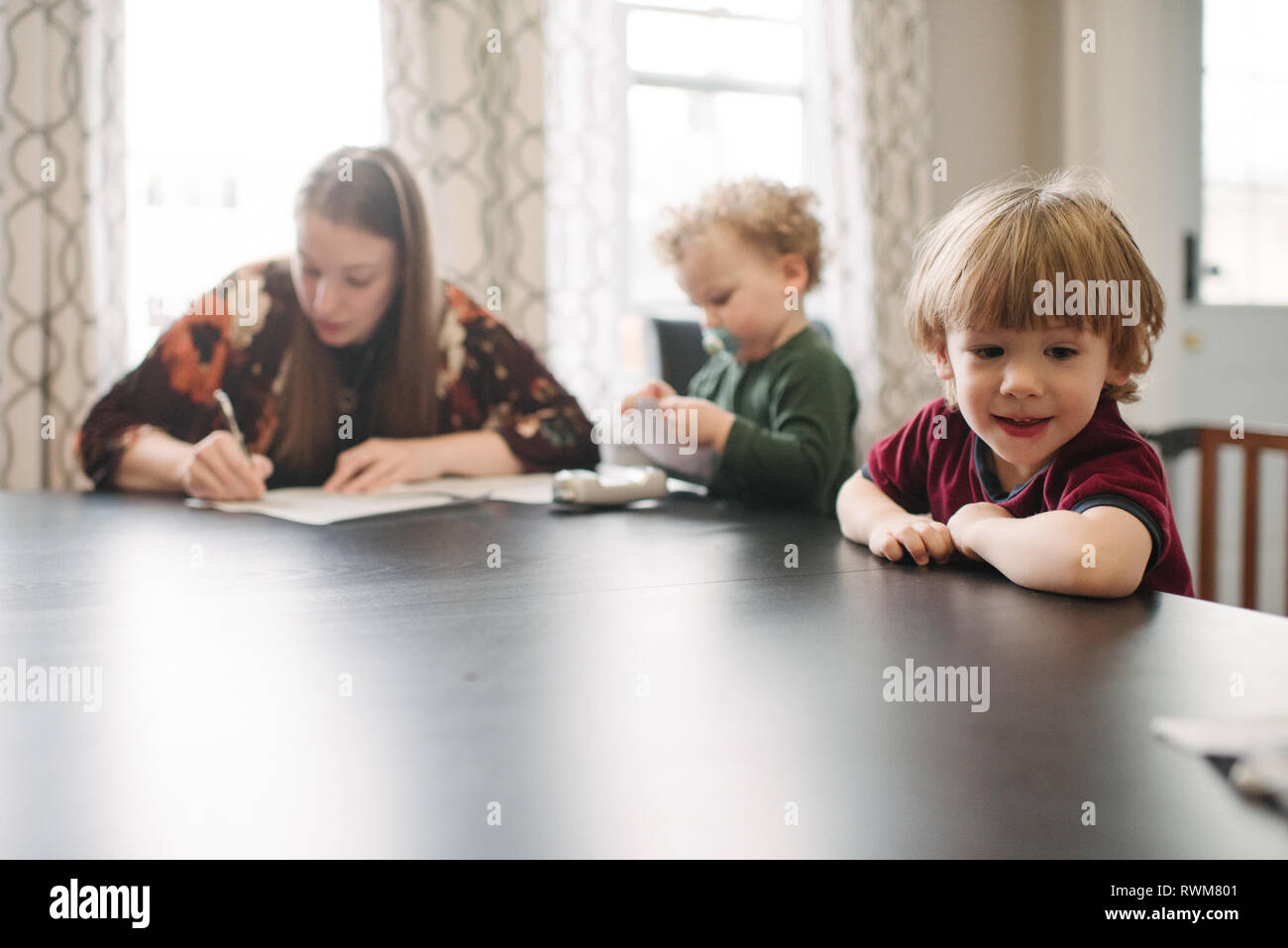 Madre forma di riempimento con figli giocando al tavolo Foto Stock