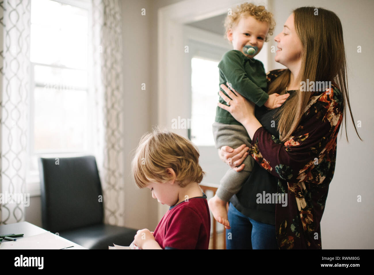 Ragazzo giocando al tavolo, madre accanto a lui Foto Stock