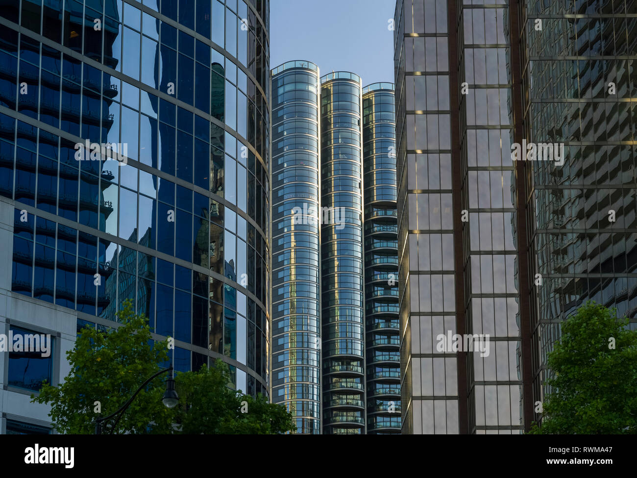 Grattacielo edifici per uffici e condomini con facciata di vetro che riflette il blu del cielo e degli edifici adiacenti; Vancouver, British Columbia, Canada Foto Stock