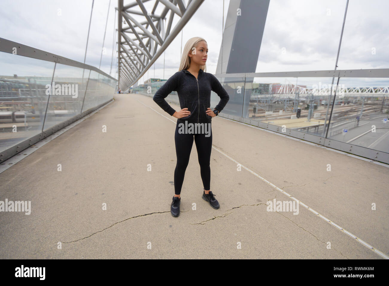 Bionda bellezza femminile in nero usura allenamento permanente al moderno ponte in città Foto Stock