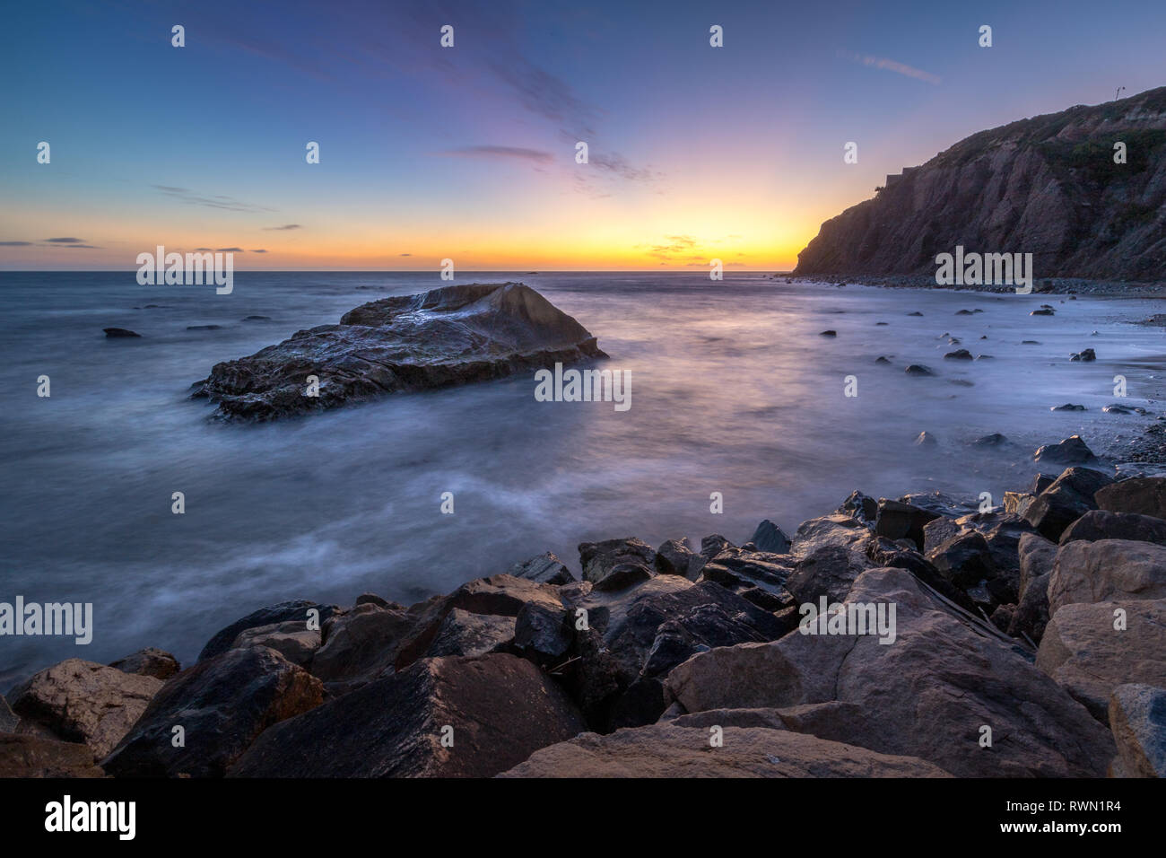 Una lunga esposizione foto di coniatura alte scogliere e le onde si infrangono in un grande rock formazione dopo il tramonto, Dana Point, California Foto Stock