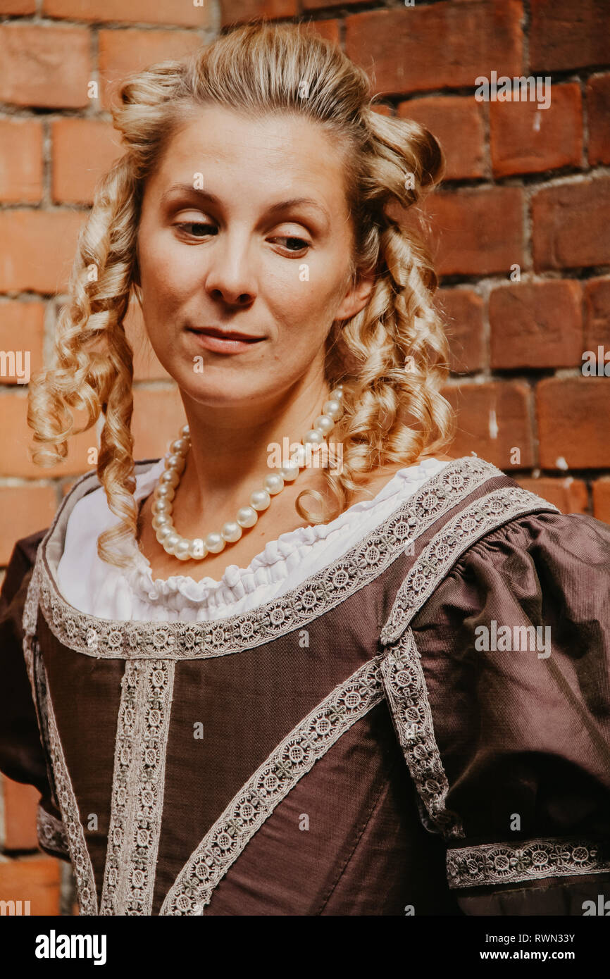 Ritratto di una giovane e bella donna in ornato abito storico- i suoi vestiti sono belle, indossa perle intorno er gola & ha arricciato i capelli biondi. Foto Stock