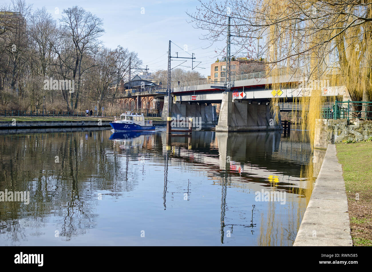 Berlino, Germania - 17 Febbraio 2019: Embankment Bellevue Ufer del fiume Spree con la scatola di acciaio trave ponte ferroviario Bellevue e una barca di polizia. Foto Stock