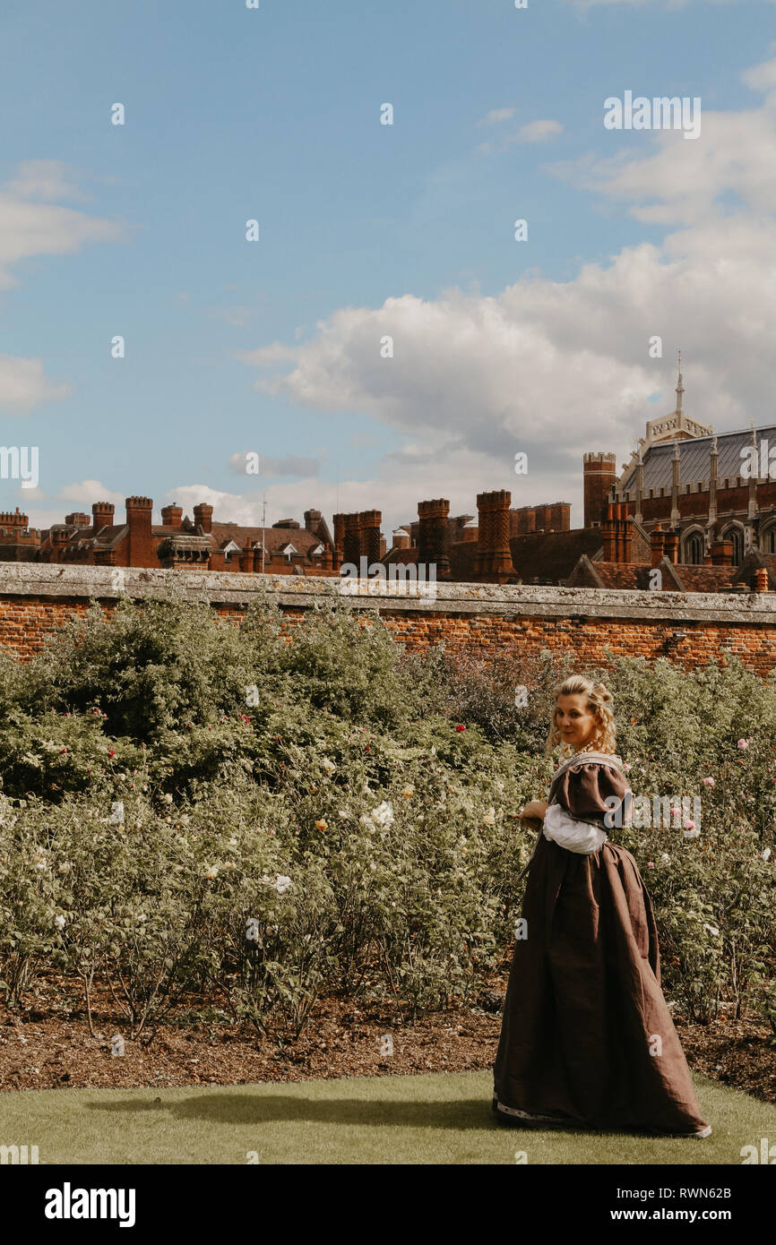 Ritratto di una giovane e bella donna in ornato abito storico- i suoi vestiti sono belle, lei è nel giardino di rose a Hampton Court Palace. Foto Stock
