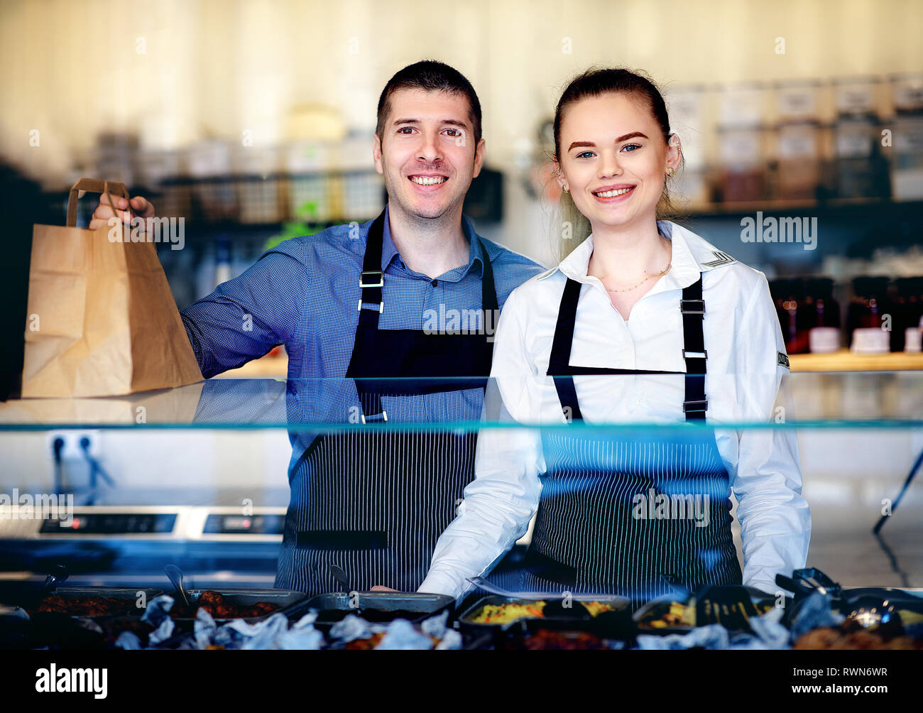 Giovane uomo e donna in piedi dietro il bancone di un ristorante. Cucina dietro Foto Stock