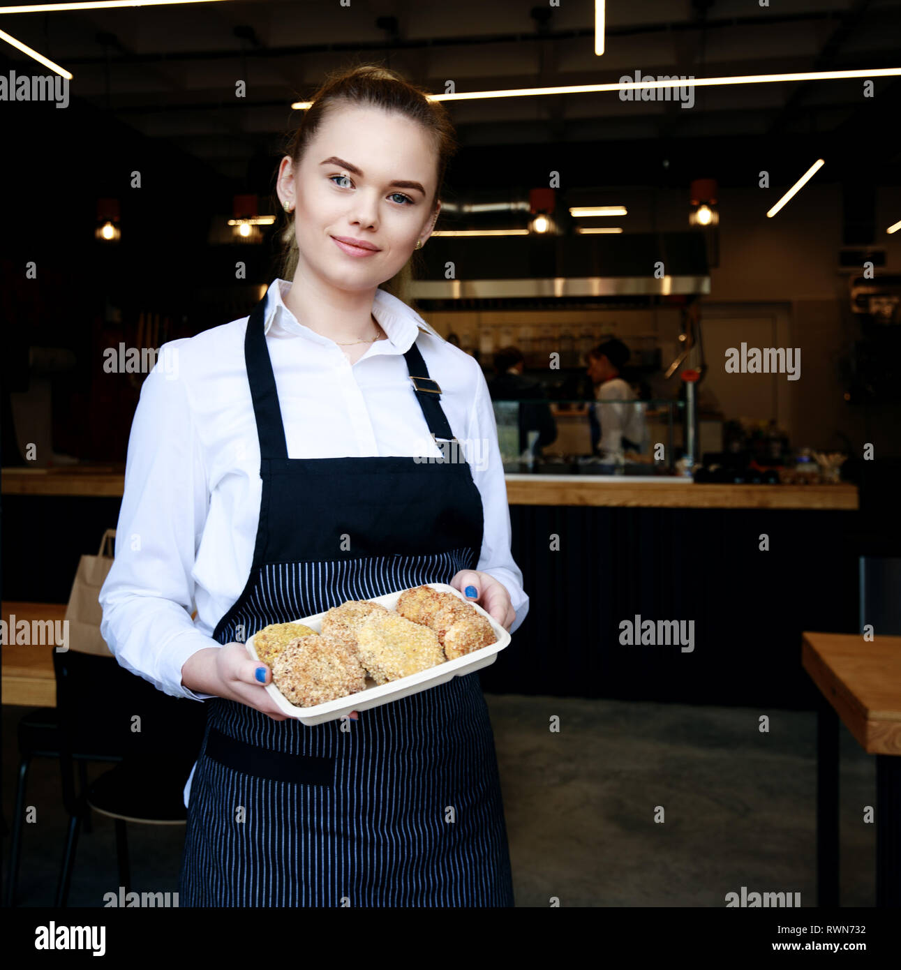 Cameriera mostra piatto di polpette di carne in un ristorante. Cibo da asporto. Cucina dietro Foto Stock