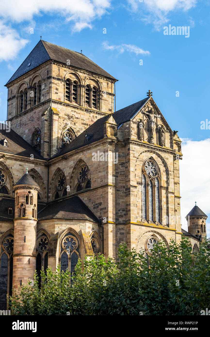 Il lato posteriore di una grande chiesa in pietra ad arco con finestre in vetro colorato e torrette rotonde con cielo blu e nuvole; Trier, Germania Foto Stock