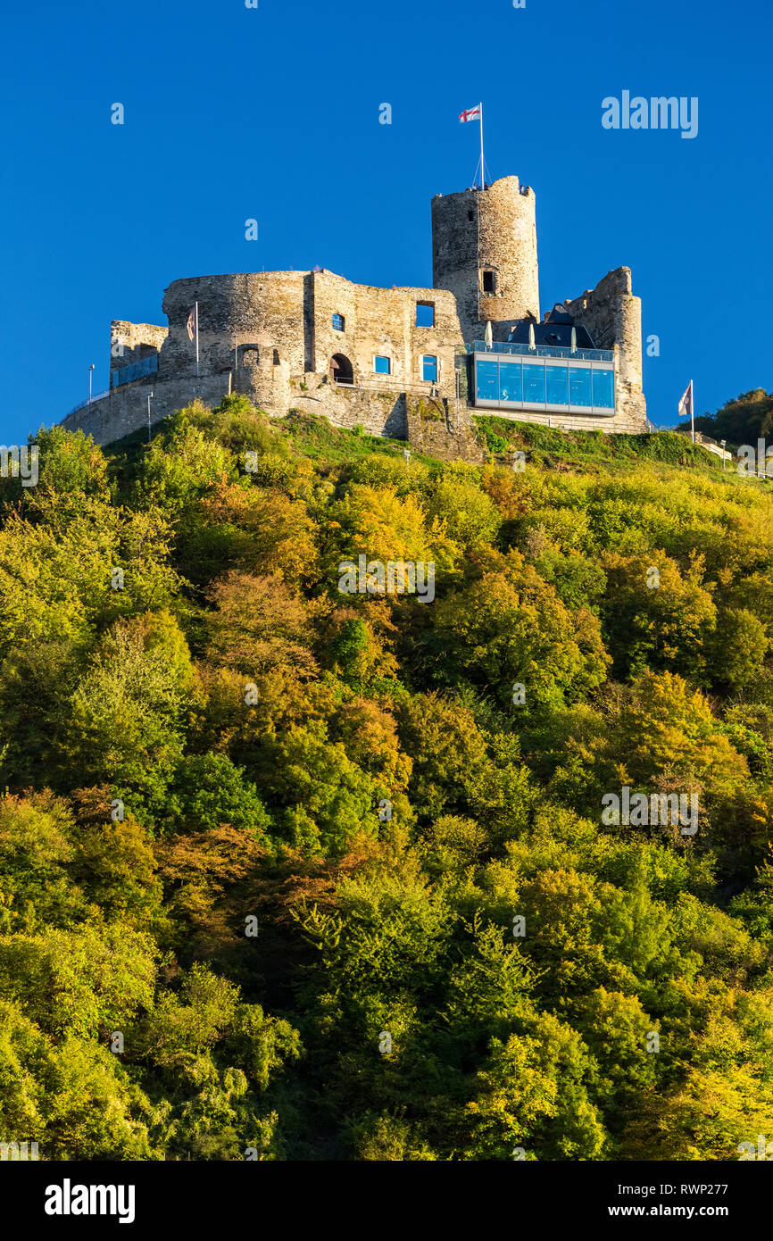 Il vecchio castello di pietra rovina sulla parte superiore della ripida collina alberata con cielo blu; Bernkastel, Germania Foto Stock