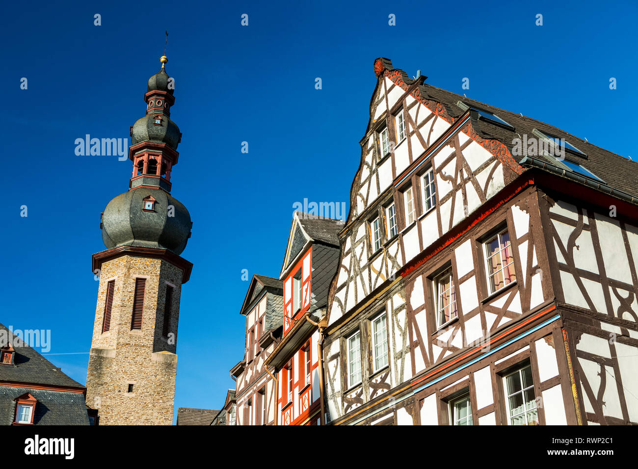 Il vecchio edificio medievale fronti con pietra alto campanile di una chiesa e di cielo blu; Cochem, Germania Foto Stock