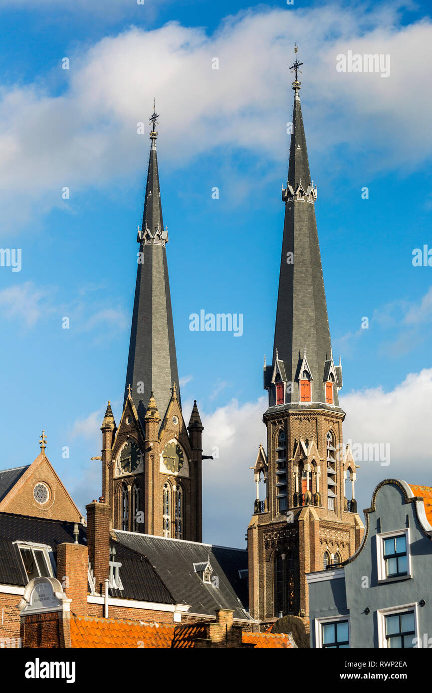 Due alte guglie della chiesa, uno con orologio e cielo blu e nuvole; Delft, South Holland, Paesi Bassi Foto Stock