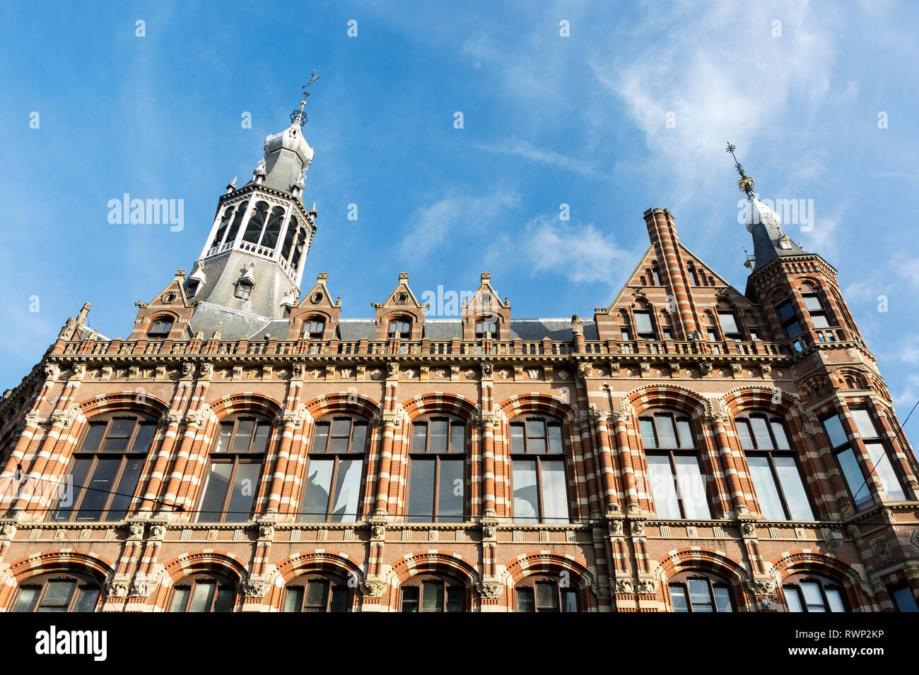 Guardando il coloratissimo facciata di edificio con chiesa Zuiderkerk steeple, cielo blu e nuvole in background; Amsterdam, Paesi Bassi Foto Stock