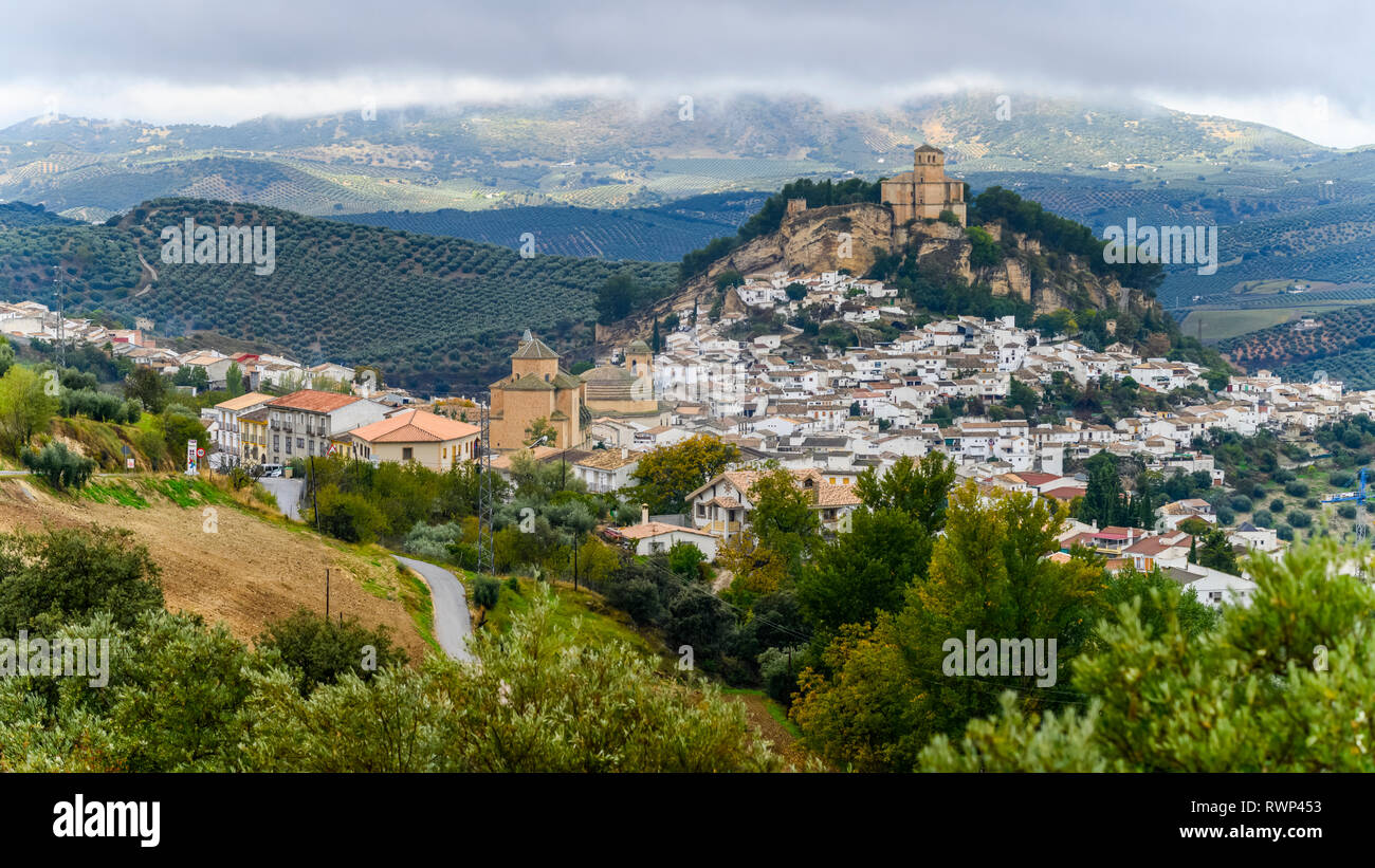 Le rovine di un castello moresco sulla cima di una collina con le case il riempimento della collina e gli uliveti delle colline; Montefrio, provincia di Granada, Spagna Foto Stock