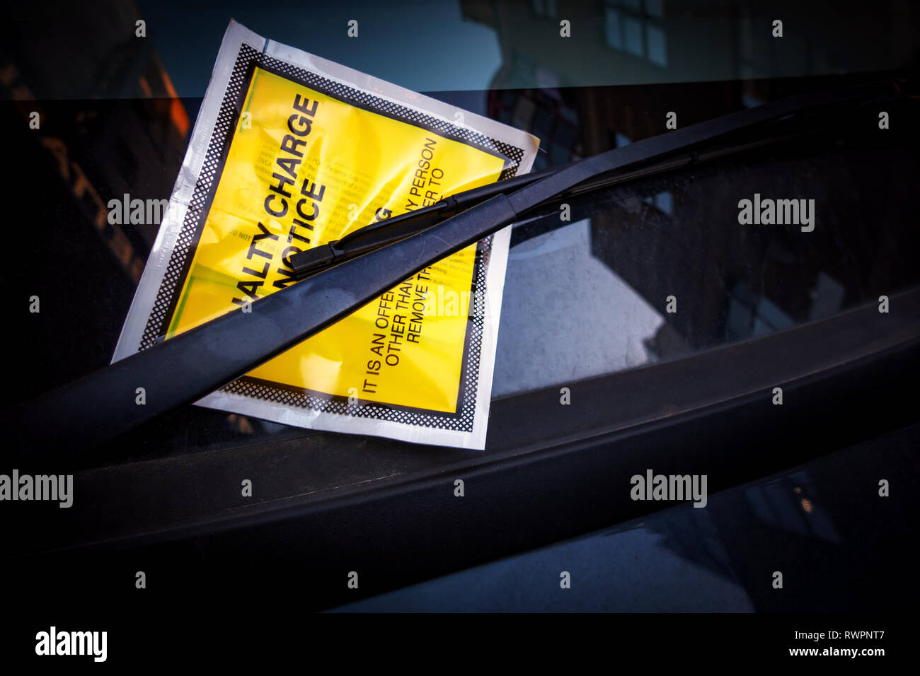 Giallo adesivo per parabrezza contenente una penalità fissa Parcheggio Avviso di carica per il parcheggio illegale ammenda tassa bloccato su di un parabrezza di automobile. Foto Stock