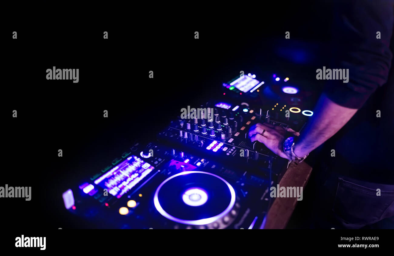 Morbida vista di man mano disc jockey di miscelazione e miscelazione di brani musicali sul suo ponte nelle tenebre di una parte o di un night club.Copia spazio per il testo. Foto Stock