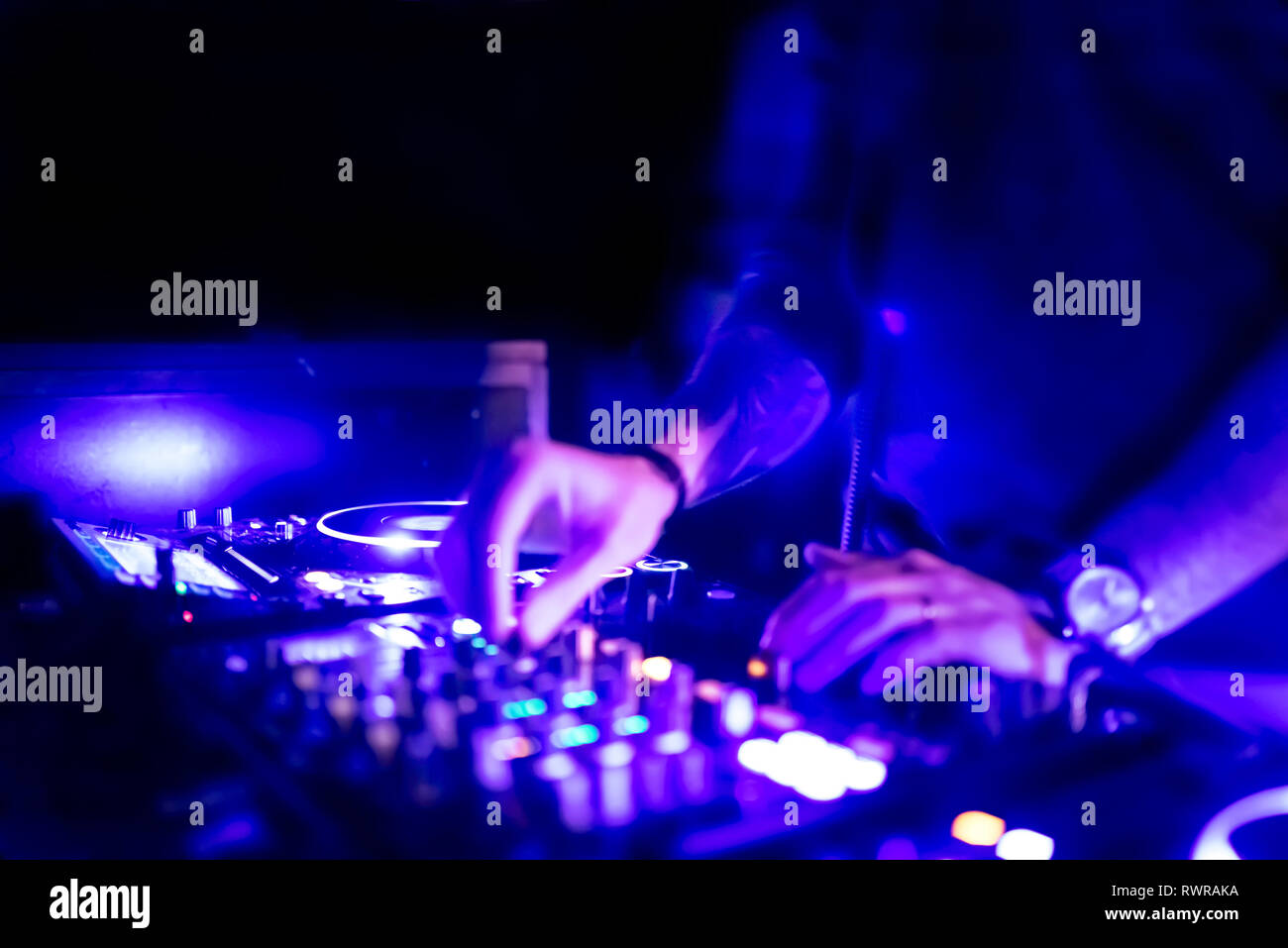 Morbida vista di man mano disc jockey di miscelazione e miscelazione di brani musicali sul suo ponte nelle tenebre di una parte o di un night club.Copia spazio per il testo. Foto Stock