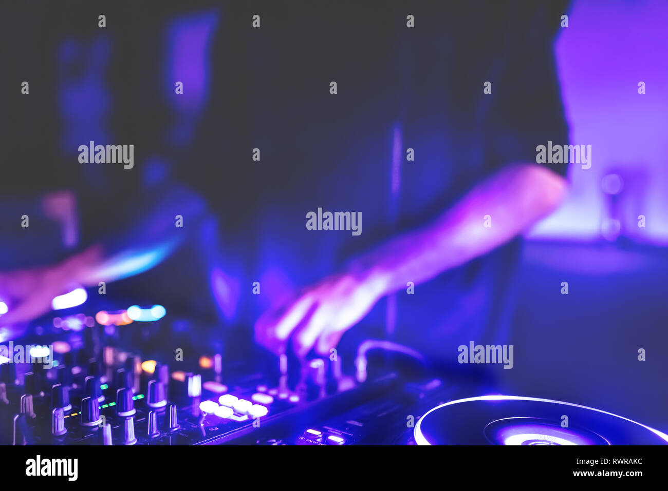 Morbida vista di man mano disc jockey di miscelazione e miscelazione di brani musicali sul suo ponte nelle tenebre di una parte o di un night club.Copia spazio per il testo. Foto Stock