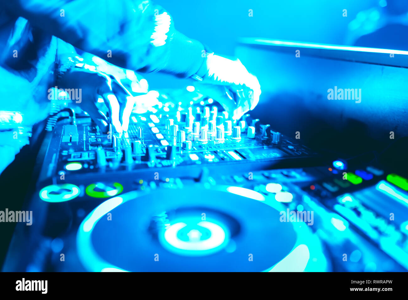 Morbida vista di man mano disc jockey di miscelazione e miscelazione di brani musicali sul suo ponte nelle tenebre di una parte o di un night club.Copia spazio per il testo. Foto Stock