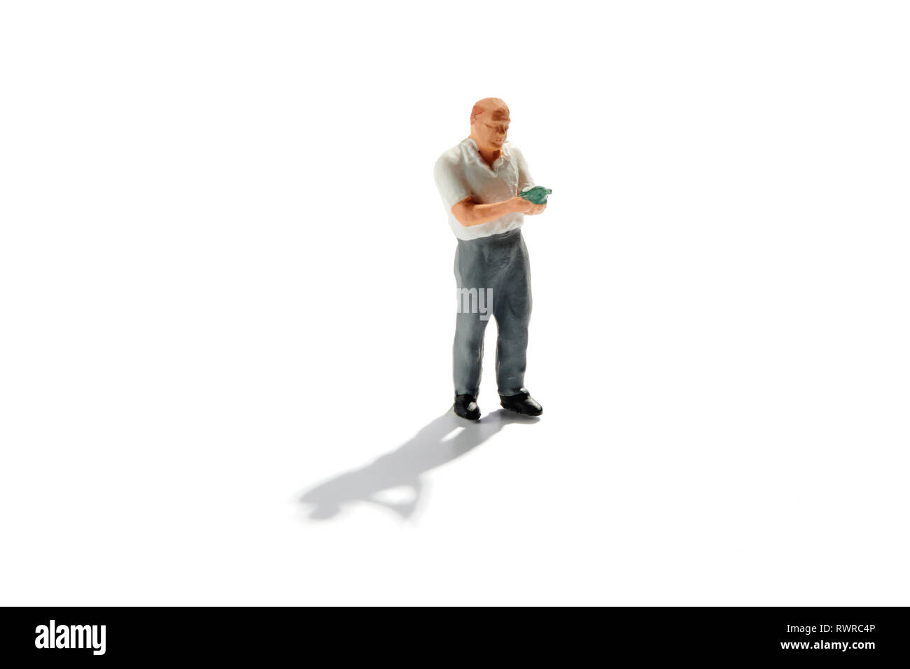 Sommelier in miniatura la lettura di una etichetta di vino su una bottiglia di vino d'annata prima di eseguire l'abbinamento con il cibo isolato su bianco con ombra e spazio di copia Foto Stock