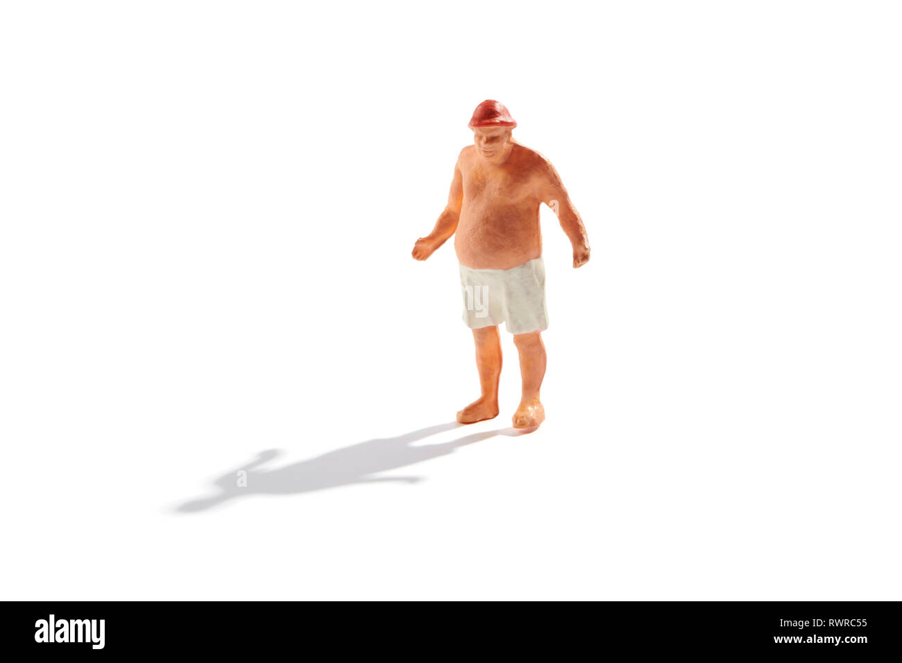 Obesi uomo in miniatura con grandi fat Panza in tronchi di balneazione in piedi su una spiaggia isolata su bianco con ombra Foto Stock