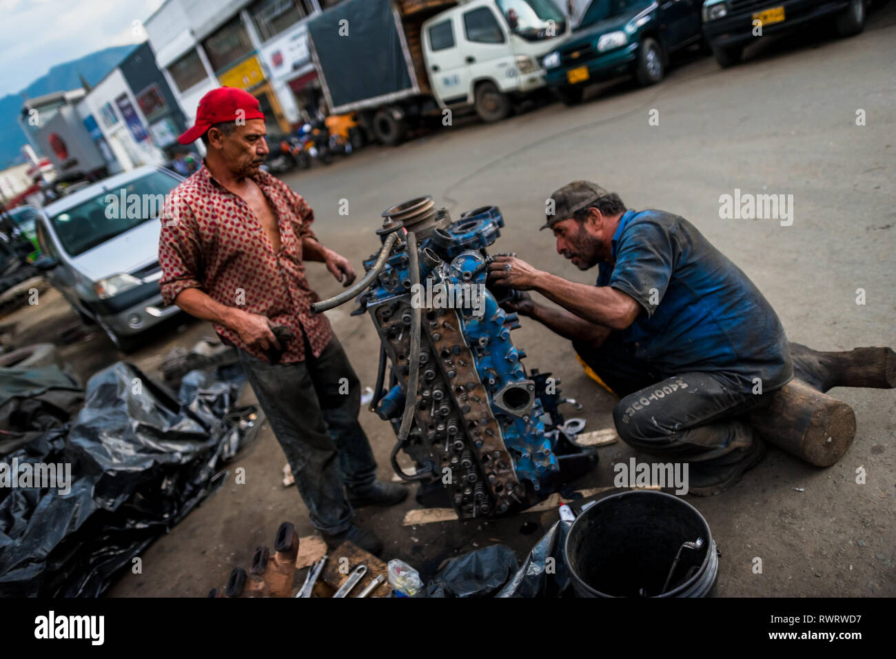 Colombiano meccanica auto lavorare su un motore del carrello di fronte a una riparazione auto shop in Barrio triste, Medellín, in Colombia. Foto Stock