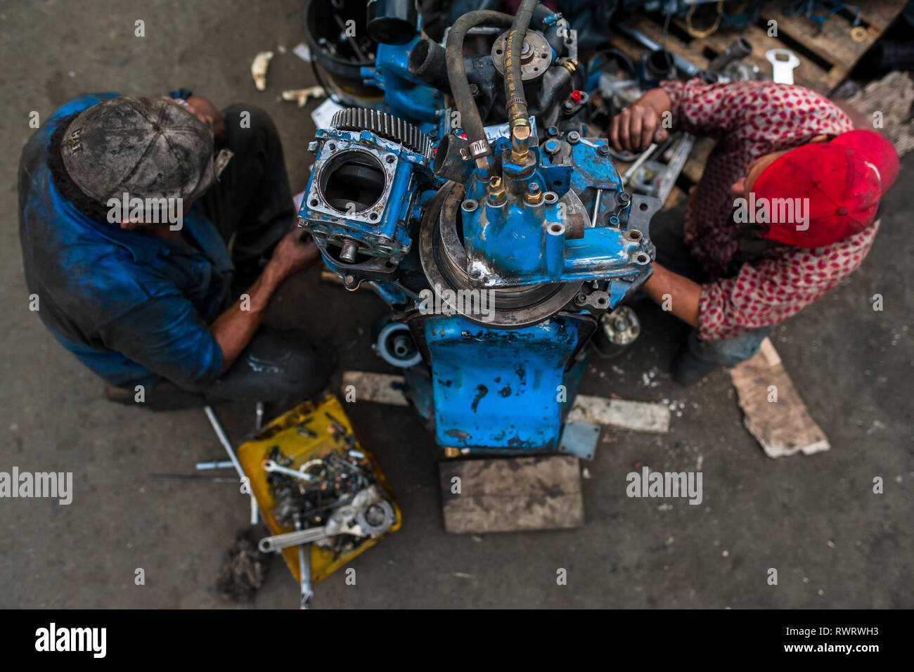 Colombiano meccanica auto lavorare su un motore del carrello di fronte a una riparazione auto shop in Barrio triste, Medellín, in Colombia. Foto Stock