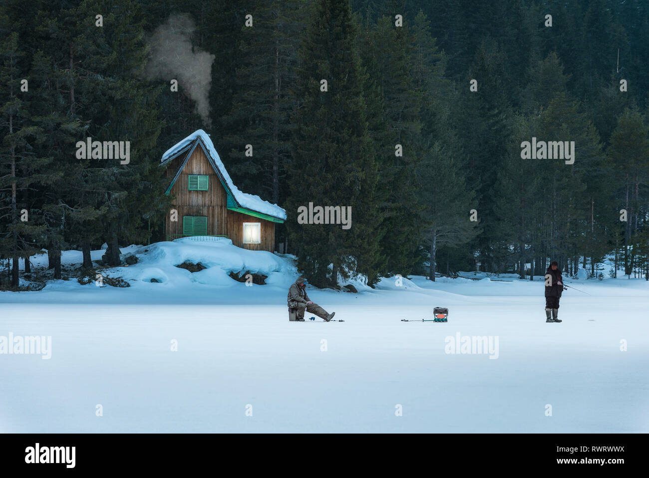 Poliana Shiroka dam, Bulgaria. 03,02,2019: Piccola casa in legno in montagna. Lago ghiacciato di fronte coperta di neve. Il ghiaccio fishermans davanti. Foto Stock