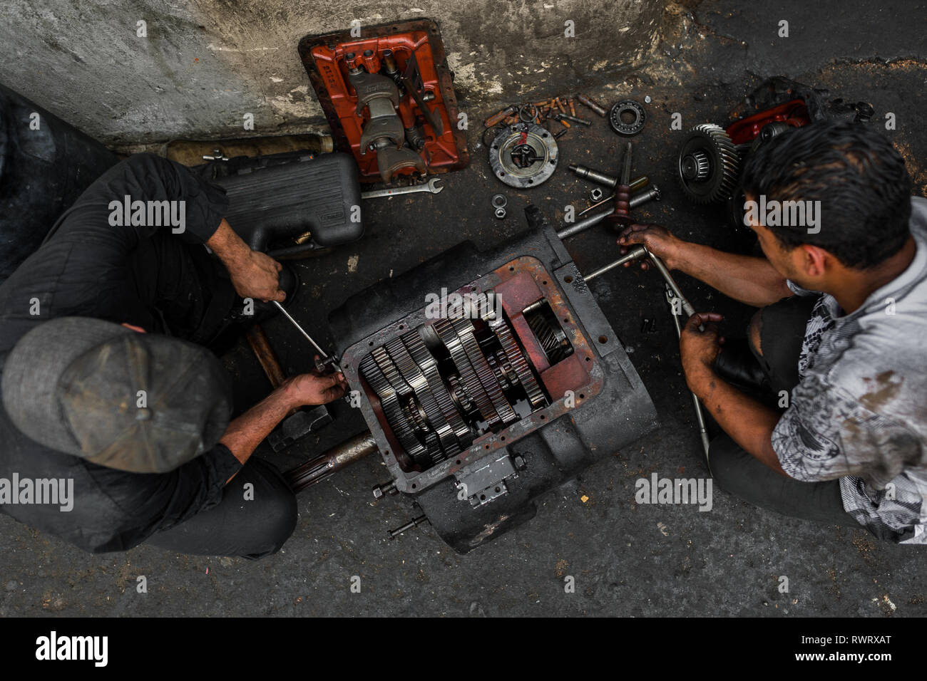 Colombiano meccanica auto lavorare su una trasmissione in una riparazione auto shop in Barrio triste, Medellín, in Colombia. Foto Stock