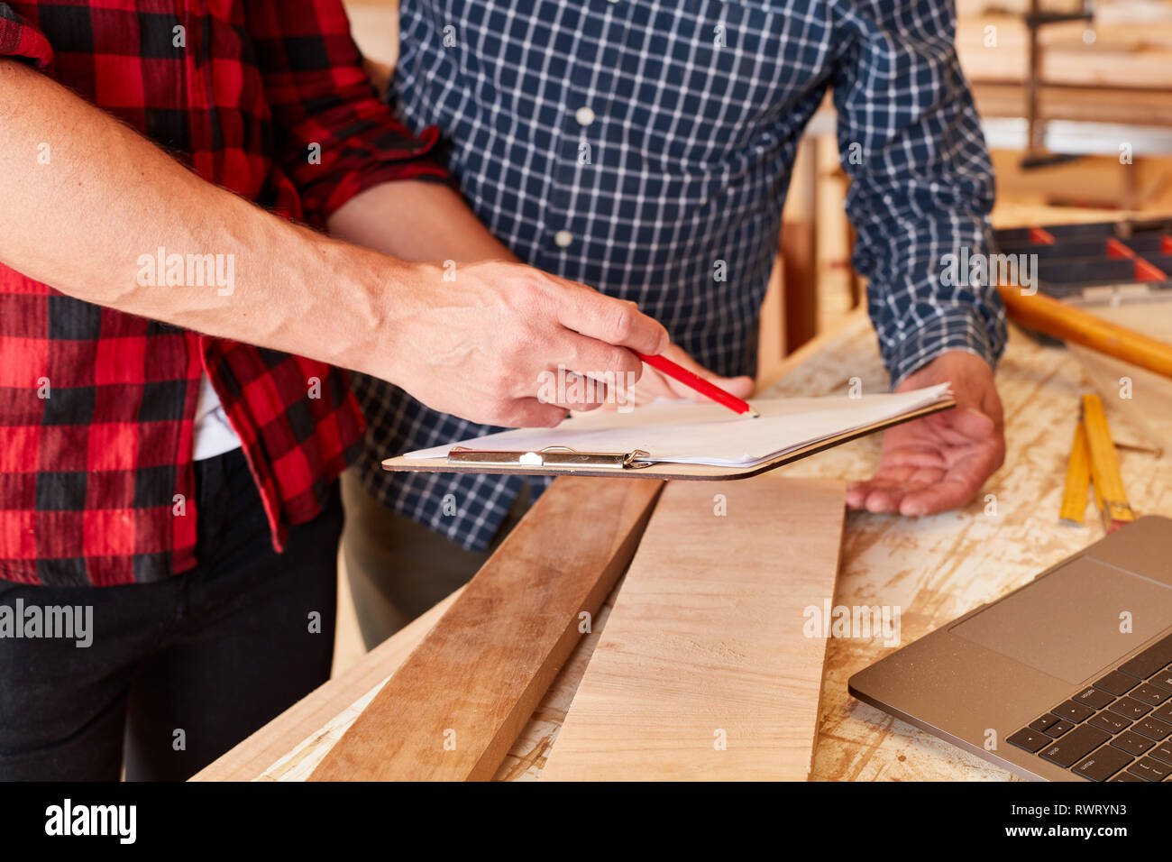 Due artigiani con la lista di controllo nel laboratorio di falegnameria sono la pianificazione di un lavoro Foto Stock
