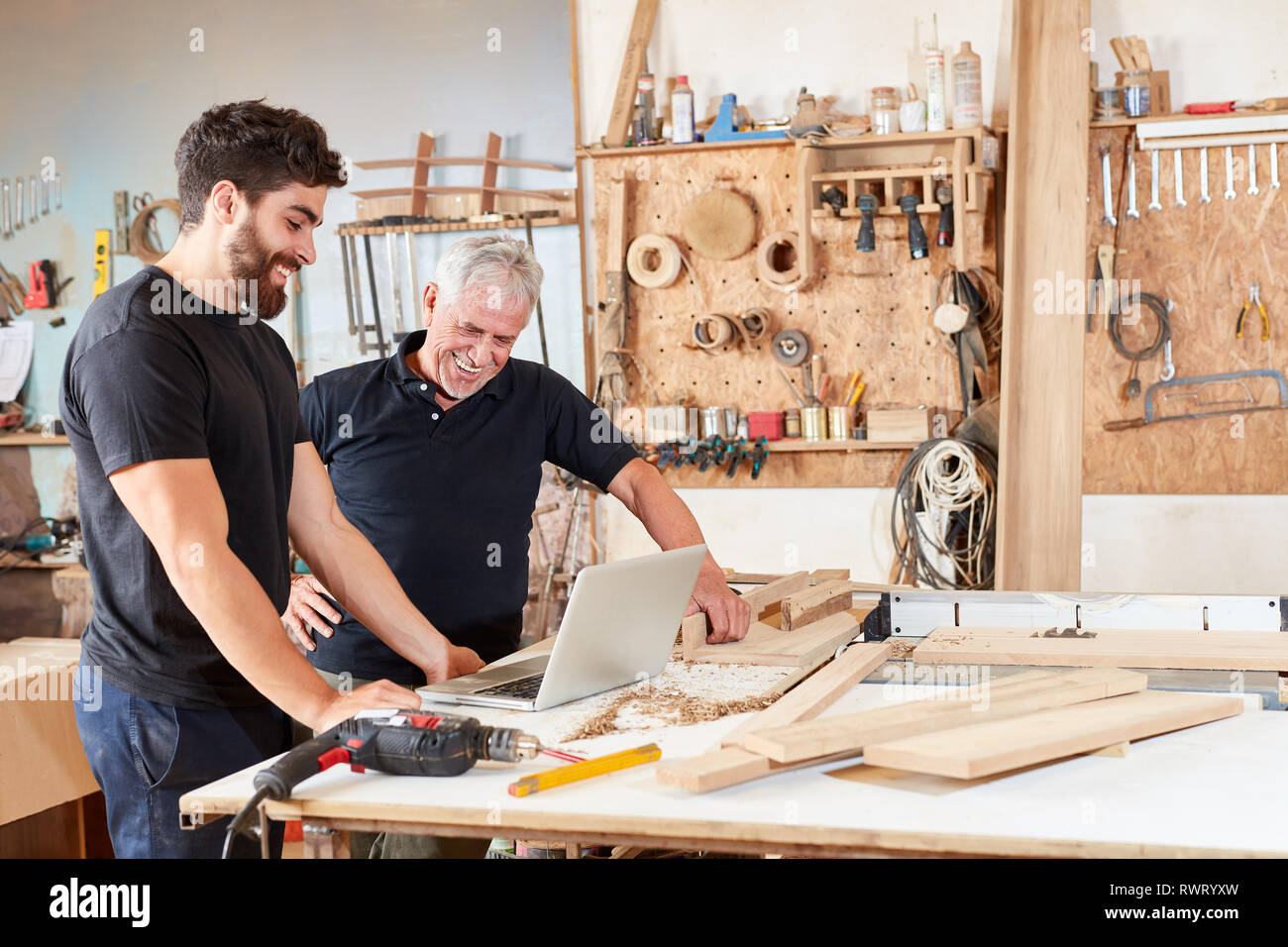 Senior e artigiano apprendista insieme al computer portatile in officina Foto Stock