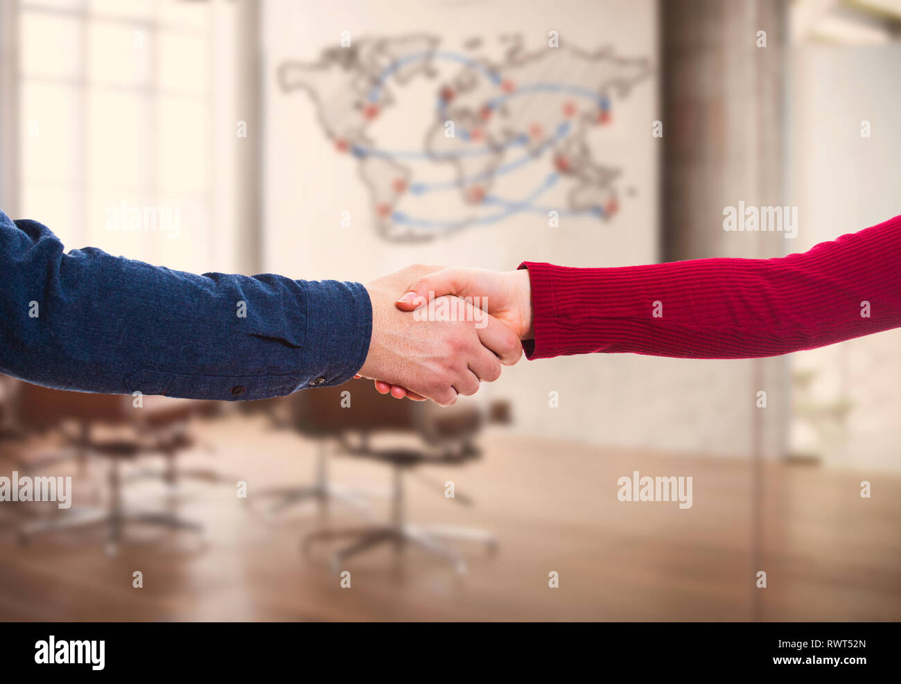 L uomo e la donna di handshake ufficio su sfondo al coperto con mappa del mondo. Attività di partenariato e di collaborazione tra i diversi paesi. Il commercio globale Foto Stock