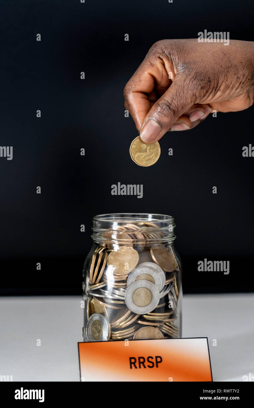 African American donna nigeriana la caduta delle monete nella giara di RRSP Foto Stock