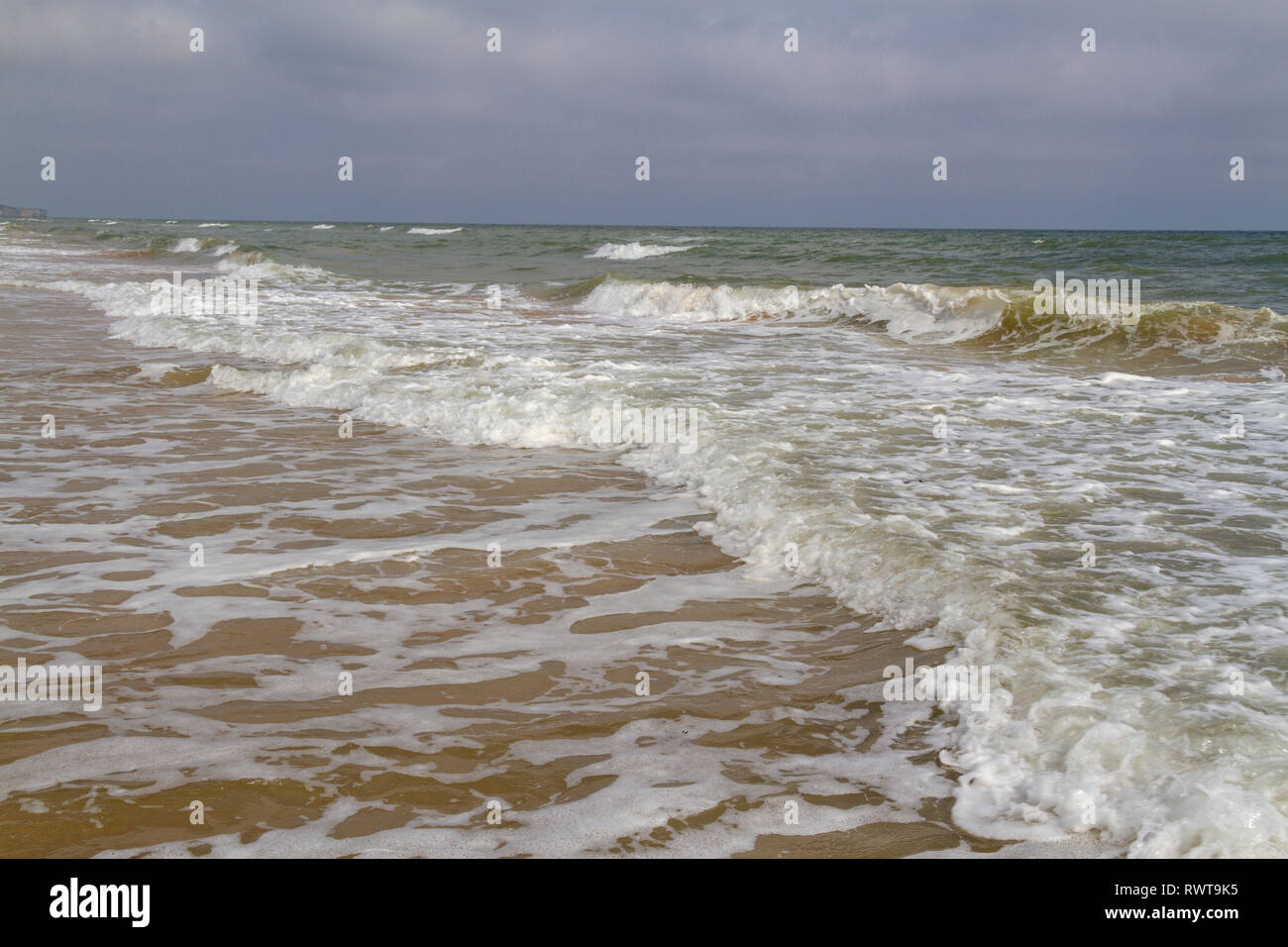 Onde che si infrangono sulla spiaggia sabbiosa che è Omaha Beach in Normandia vicino a Colleville-sur-Mer, Francia. Foto Stock