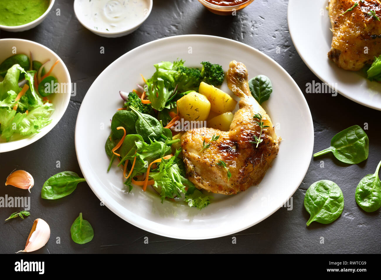 Pollo alla griglia della gamba con patate e insalata verde nero sul tavolo di pietra. Gustoso piatto per la cena. Foto Stock