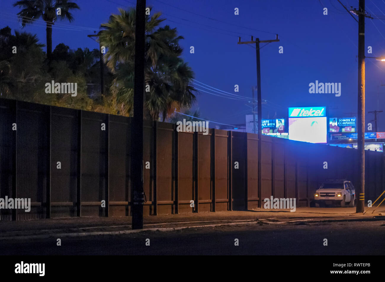 Recinzione di confine nel centro cittadino di Calexico California, in prima serata, appena ad est del centro cittadino di porto di entrata, recinto è relativamente breve e quindi facilmente scalato. Foto Stock
